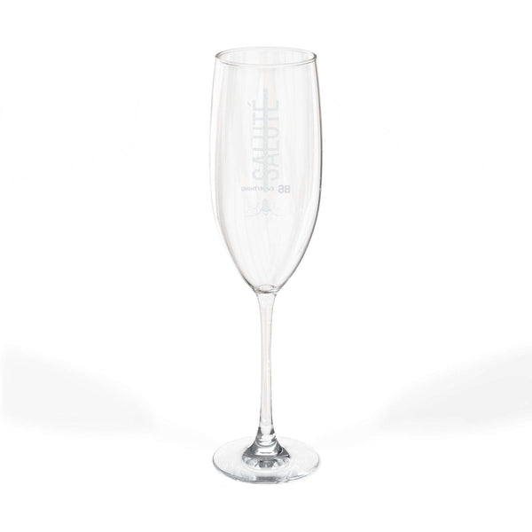 Single clear glass champagne flute with SALUTÉ and 86 EVERYTHING printed on the side.