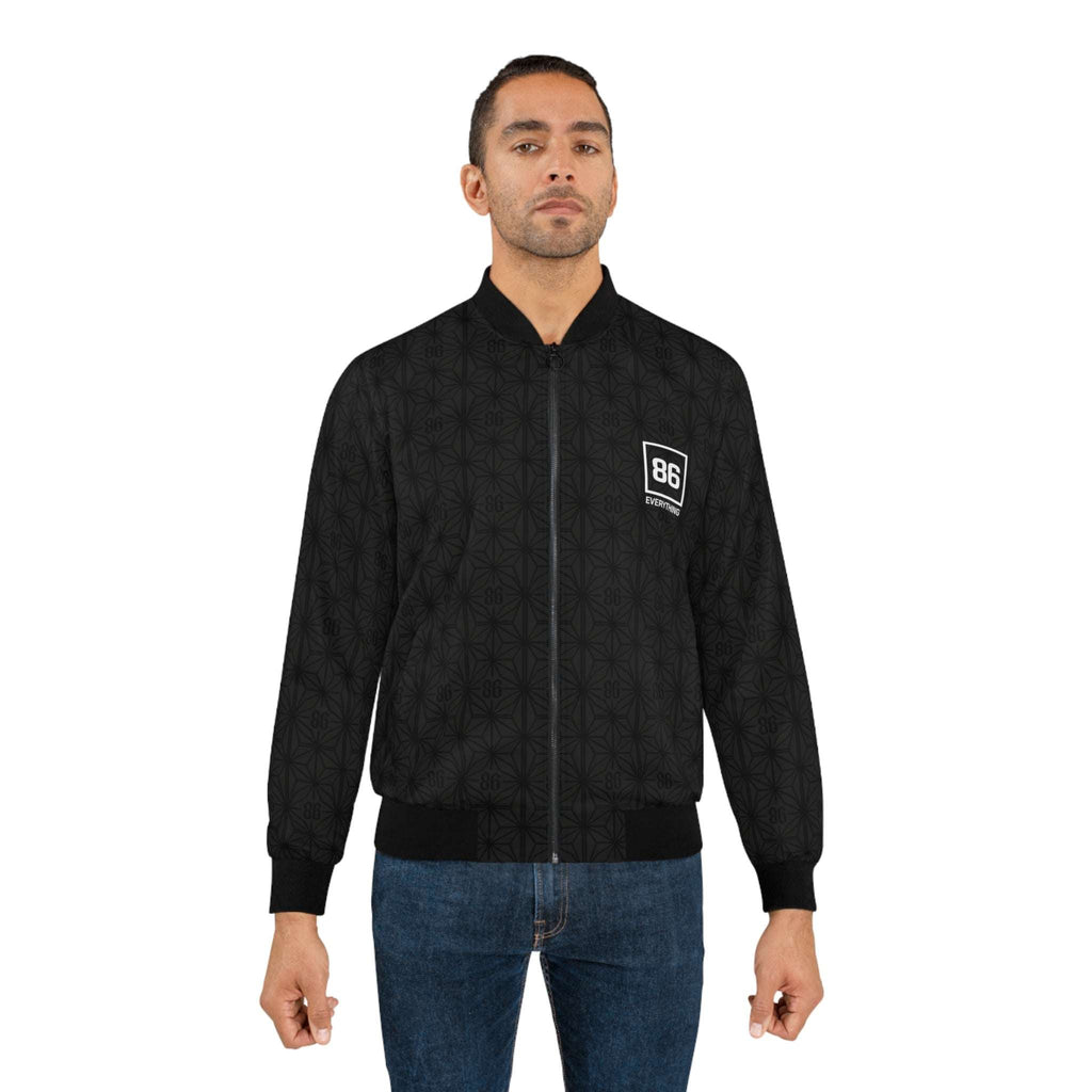 Man wears a black 86 EVERYTHING patterned zip-up bomber jacket with a white logo patch on the chest.