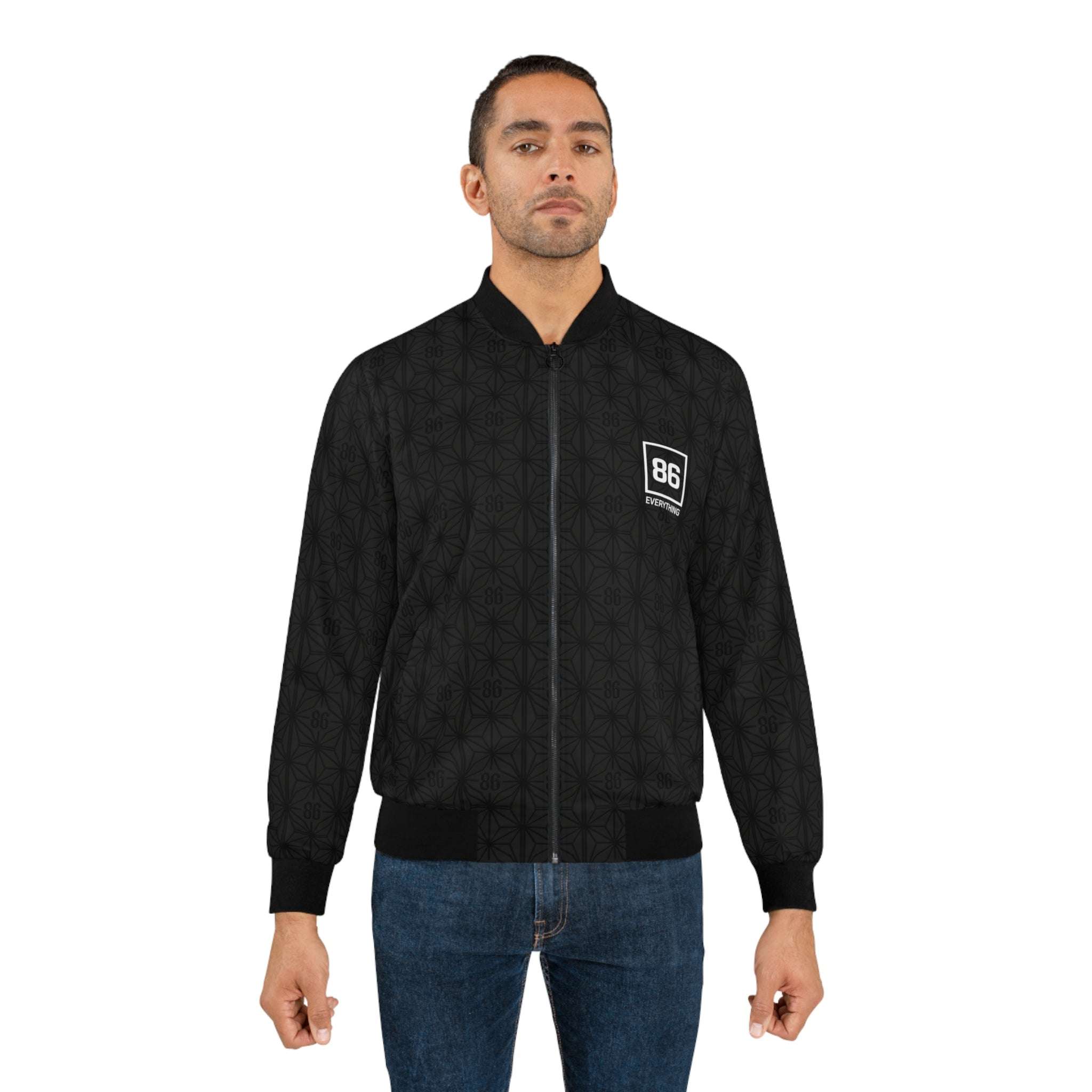 Man wears a black 86 EVERYTHING patterned zip-up bomber jacket with a white logo patch on the chest.